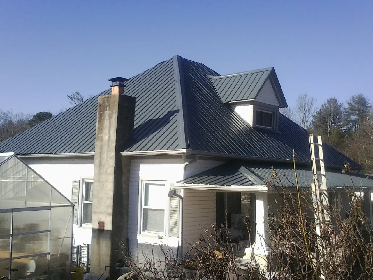 Dark blue standing seam metal roof on a white farmhouse with dormer — Slate & Tile Roof Repair by Roofing Brothers in Taylor Ridge