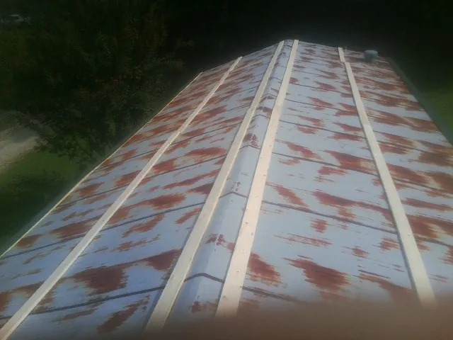 Rusted metal roof panels with new wood purlins before replacement — Storm Damage Roof Repair in Taylor Ridge by Roofing Brothers