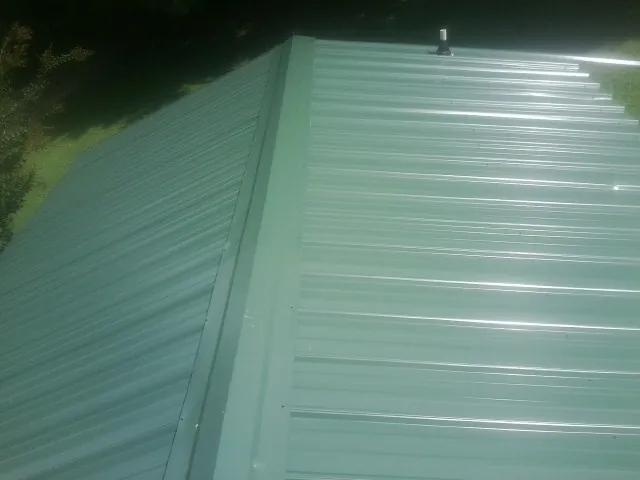 New green metal panels meeting at the ridge of a roof — Flat Roof Repair work by our crew in Taylor Ridge