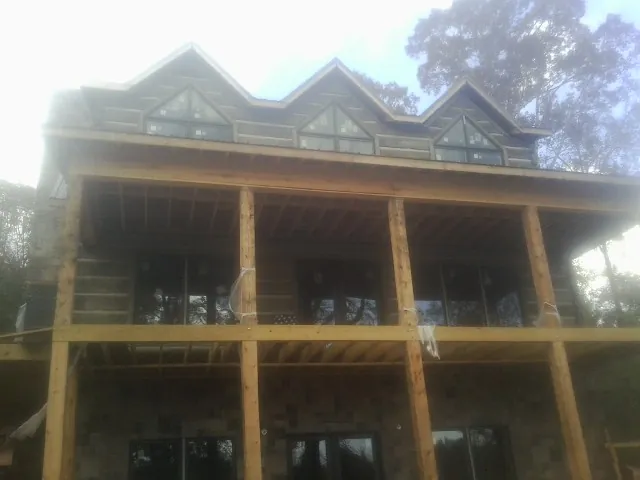 Dormers and porch framing on a large log home under construction — Roof Coating work by our crew in Taylor Ridge
