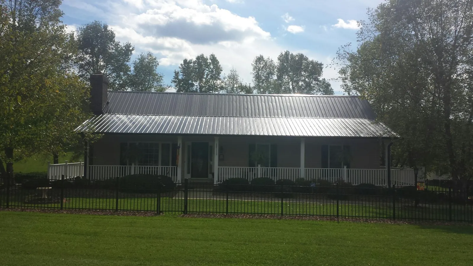 Gray metal roof on a brick ranch with a full width front porch — Gutter Guard Installation work by our crew in Taylor Ridge