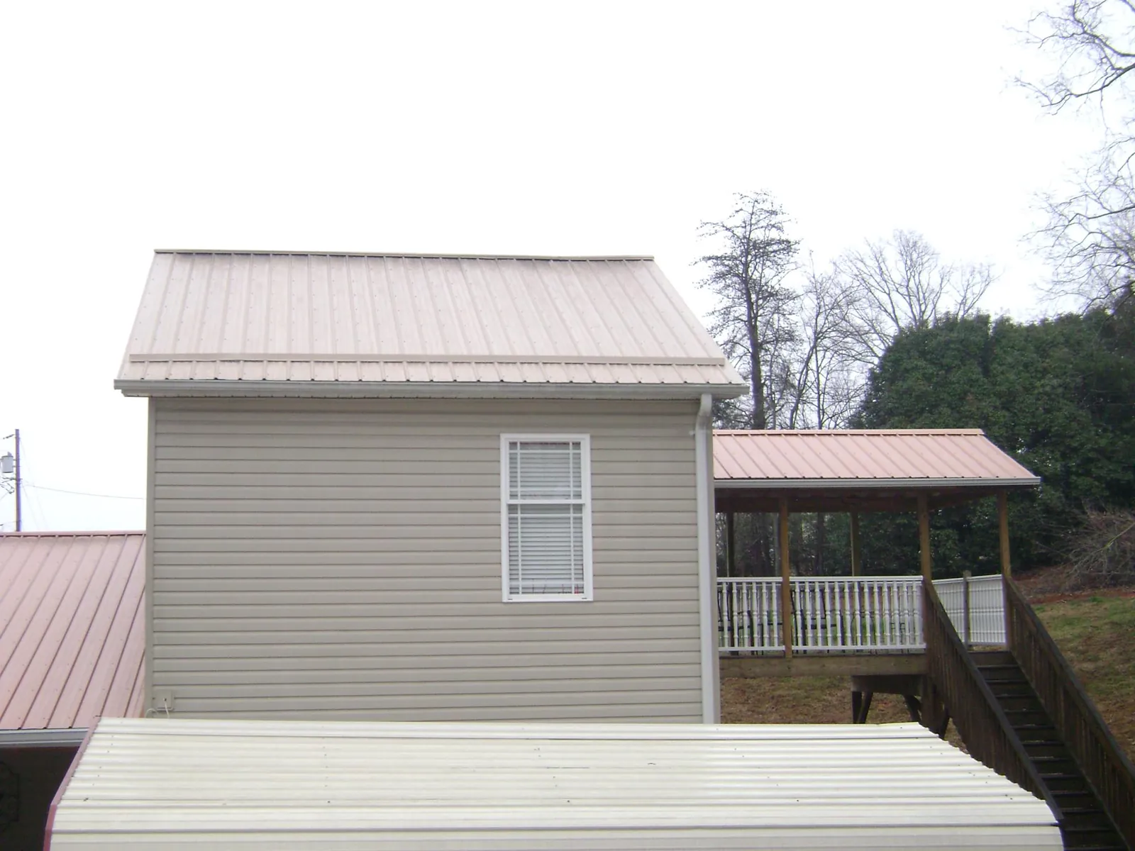 Tan metal roofs on a two story addition and attached porch, from a Roof Replacement job in Taylor Ridge