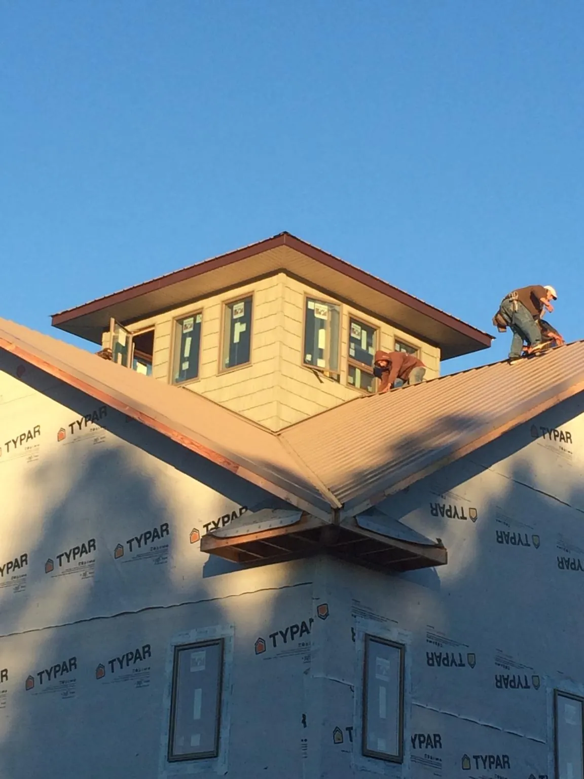 Roofers working around a rooftop cupola on a new metal roof at sunset — Roof Waterproofing in Taylor Ridge by Roofing Brothers
